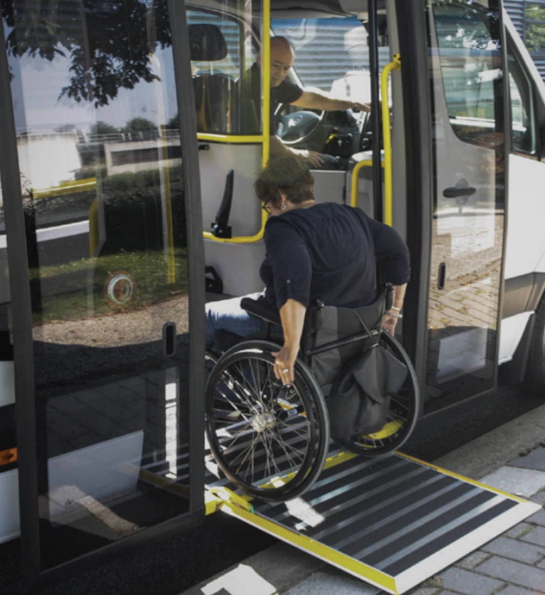 A wheelchair user entering a low floor city bus via a small fold out ramp